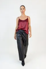 Pantalón cargo de corte recto y tiro medio, confeccionado en eco cuero negro. Presenta bolsillos laterales tipo cargo, cierre frontal con botón y bragueta, y un acabado liso con brillo sutil.