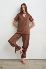 Pantalón recto marrón de lino y algodón, con tiras regulables en los tobillos para ajustar.