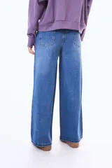 Jean de corte wide leg en color azul medio con efecto lavado. Presenta tiro medio, cierre frontal con botón y bolsillos laterales y traseros.