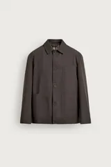 Sobrecamisa regular fit color marrón oscuro de algodón con estructura canvas, cuello solapa, manga larga, bolsillos frontales de parche y cierre de botonadura. Forro interior a cuadros en tonos marrón y beige.
