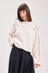 Sweater de punto color negro, de corte holgado y manga larga, con detalle de bordado calado en los hombros y a lo largo de las mangas.