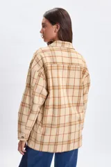 Sobrecamisa de corte holgado con diseño de cuadros en tonos beige y rosado, cuello camisero, cierre frontal con botones y bolsillos delanteros en el pecho.