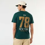 Remera verde oscura de manga corta con cuello redondo. Cuenta con un gran estampado en la espalda que incluye el número "78" en tono tostado y el texto "NEW YORK" en blanco, junto con tipografías complementarias.