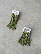Caravanas colgantes artesanales FLUSS modelo Fiesta Stone, en color verde. Presentan un aplique superior texturizado con mix de piedras y pedrería, del cual desprenden flecos de hilo verde, cadenas plateadas, abalorios y piedras colgantes.