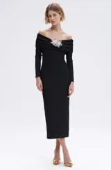 Vestido midi negro de hombros descubiertos, confeccionado en punto con forro, canesú drapeado en el escote y detalle de apliques florales tridimensionales con brillos en el frente. Tiene mangas largas y corte ajustado.