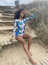 Traje de baño enterizo de lycra reciclada con estampado de hojas y flores en tonos azul, verde y rosa. Tiene mangas largas, cierre en la espalda y protección SPF 50.