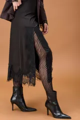 Falda midi de color negro con diseño irregular y terminación en encaje delicado en el ruedo.