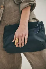 Neceser de cuero negro con cierre superior y detalle de borla y etiqueta con logo.