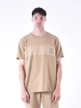 Remera de manga corta color tostado con textura acanalada horizontal y panel liso en el pecho. Presenta un estampado gráfico pequeño en el lado izquierdo del pecho con la inscripción Exclusive Premium Edition.