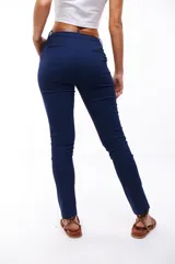 Pantalón azul marino de corte skinny, con bolsillos laterales y traseros. Se ajusta a la cintura con cinturón de cuero marrón.