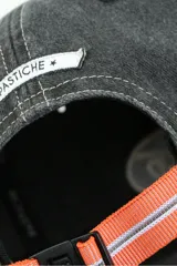 Gorro con visera color gris oscuro, con bordado blanco en el frente y hebilla trasera para ajuste.