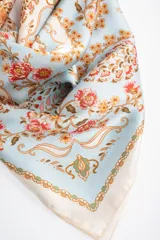Pañuelo cuadrado de poliéster con estampado tipo paisley y floral en tonos celestes, blancos, rosados y anaranjados.