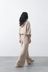 Pantalón de corte holgado y pierna ancha, con cintura elástica ajustable mediante cordón. Presenta bolsillos laterales y costuras verticales decorativas que recorren el frente de las piernas.