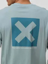 Remera de manga larga en color verde azulado, con corte regular fit. Presenta un estampado cuadrado en la espalda con una X grande y detalles de marca en la manga.