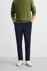 Pantalón de corte slim fit confeccionado en tejido elástico, con cintura elástica, cierre frontal con cremallera y botón, bolsillos laterales y bolsillos traseros de vivo.