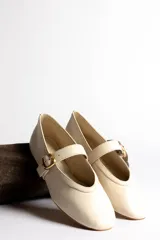 Ballerinas color crema con correa sobre el empeine y hebilla dorada.