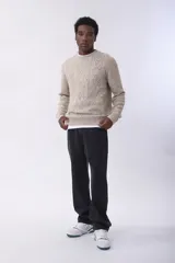 Sweater de punto con diseño de rombos en relieve, color beige jaspeado, de cuello redondo y manga larga.