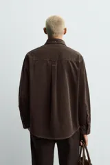 Camisa de corte relajado confeccionada en pana de algodón, con cuello solapa, manga larga con puños abotonados y cierre frontal de botones.