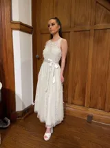 Vestido largo blanco de tul con escote redondo, detalles bordados y apliques en forma de flores.