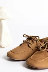 Mocasín de cuero marrón con cordones, diseño de puntera cuadrada y costuras visibles.