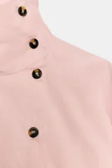 Camisa de cuello alto con cierre frontal cruzado mediante botones de carey. Presenta mangas largas con puños rectos y un diseño de bajo asimétrico con corte holgado.