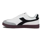 Championes casuales blancos para mujer, con detalles en negro y gris. Presentan un diseño de corte bajo, cordones blancos y suela de goma marrón oscuro. El logo lateral es una forma estilizada en color negro.