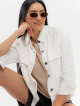 Campera de jean blanca con bolsillos frontales con solapa y botones metálicos oscuros.