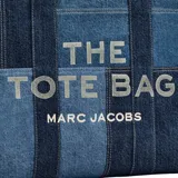 Bolso tipo tote de Marc Jacobs confeccionado en denim azul con diseño de paneles en diferentes tonos. Presenta el logo 'THE TOTE BAG' estampado en la parte frontal y doble asa superior.