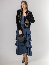 Falda midi de micro corderoy azul marino, con diseño de volados escalonados y cintura elástica. Presenta un corte asimétrico, siendo ligeramente más corta en la parte frontal.