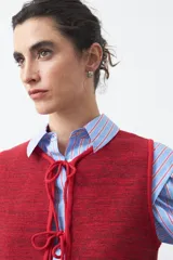 Chaleco de punto con efecto jaspeado en color azul, con diseño sin mangas, escote redondeado y cierre frontal mediante lazos ajustables.