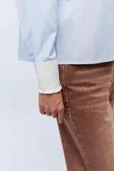 Camisa celeste a rayas con cuello clásico y puños blancos con volados.