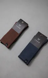 Pack de dos pares de medias de algodón con textura acanalada, una en color negro y otra en color chocolate. Ambas cuentan con una pequeña etiqueta textil con el logo de tijeras en el borde superior.