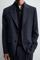 Blazer de corte regular confeccionado en lana de origen italiano. Presenta cuello con solapas de muesca, cierre frontal de un botón, bolsillos laterales con solapa y bolsillo de vivo en el pecho. Incluye abertura central en la espalda y forro interior.