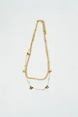 Collar doble dorado con cadena de eslabones y cadena fina con dijes de flores negras.