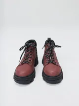 Bota acordonada de estilo montañés con suela track de goma robusta. Confeccionada en cuero con detalles de gamuza en la talonera y tirador trasero. Presenta costuras a contratono y cordones bicolores.