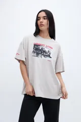 Remera gris con efecto marmolado, calce boxy, diseño fotográfico y texto en el frente.