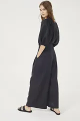 Pantalón culotte negro de lino orgánico, con cintura alta, diseño plisado y bolsillos laterales.