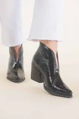 Botinetas negras de cuero charol, con corte en V en el empeine y taco geométrico.
