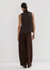 Blusa de tejido satinado color marrón, de corte recto, sin mangas y con cuello alto. Cuenta con cierre de cremallera en la parte posterior.