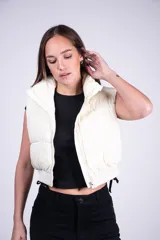 Chaleco puffer corto color blanco, con cuello elevado y cierre frontal. Cuenta con diseño acolchado y bolsillos laterales.