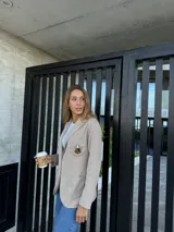 Blazer color beige de algodón con solapas y parche bordado en el pecho.