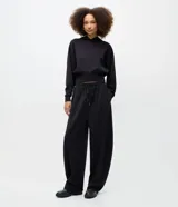 Pantalón de corte barrel con piernas anchas y cintura cónica, confeccionado en tejido de modal con acabado liso. Presenta cintura elástica con lazo ajustable y diseño fluido.