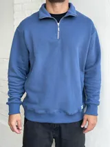 Buzo azul de felpa con cuello polo y cierre metálico a la mitad del torso.
