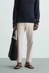 Pantalón chino de corte slim fit, confeccionado en tejido elástico. Presenta bolsillos frontales, bolsillos traseros de vivo con botón y cierre frontal con cremallera y botón.