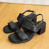 Sandalia de cuero negro con textura, estilo dos tiras anchas y taco cuadrado de madera de 5 cm de altura. Posee una tira fina ajustable en el tobillo.