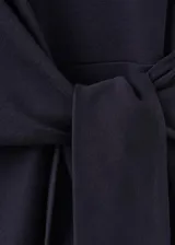 Vestido corto negro de manga corta y cuello redondo, con detalle de lazo cruzado en la cintura.