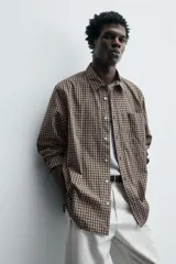 Camisa relaxed fit de algodón con estampado de cuadros en tonos marrón y beige. Cuenta con cuello solapa, manga larga con puño abotonado, bolsillo plastrón en el pecho y cierre frontal de botonadura.
