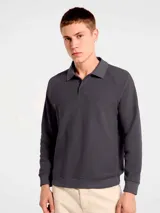 Buzo de manga larga confeccionado en tejido interlock, con cuello tipo polo y cierre frontal de dos botones. Presenta un diseño de corte clásico con puños y ruedo acanalados.