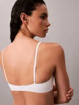 Sujetador tipo balconette Calvin Klein de la línea Cotton Modal Bare, color blanco. Presenta copas suaves sin relleno, aros flexibles para mayor sujeción, tirantes ajustables y cierre de gancho en la parte trasera. Incluye un pequeño parche con el logo de la marca en el centro.