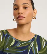 Vestido midi de corte recto, confeccionado en viscolycra con estampa de follaje en tonos verdes, azules y blancos. Presenta cuello redondo, mangas cortas y un tajo lateral en el dobladillo.
